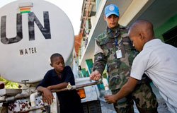 UN Photo/Ky Chung A member of the Bolivian contingent of MINUSTAH opens a water tap for a young boy.